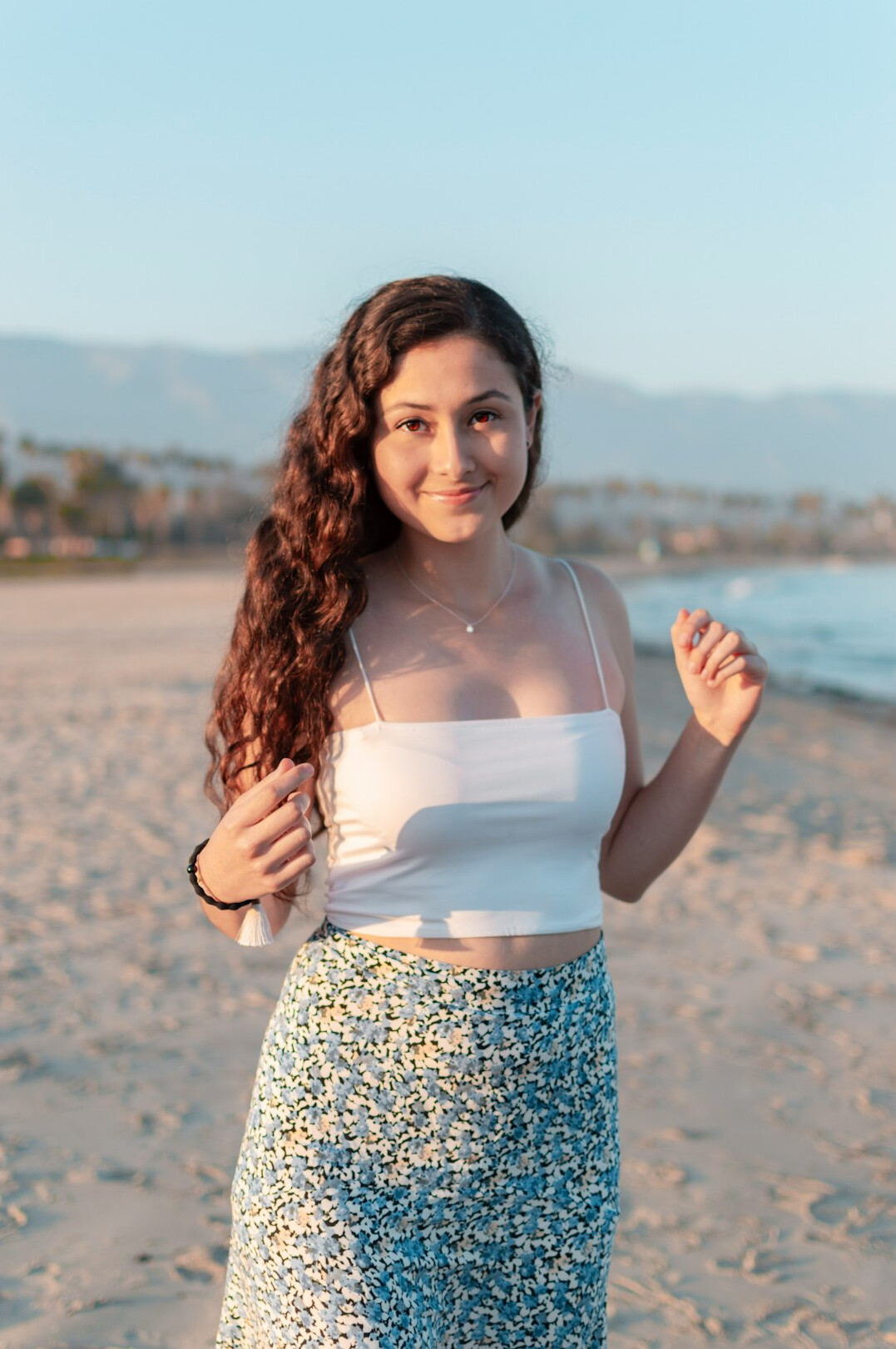 Portrait of a young woman with curly hair smiling outdoors